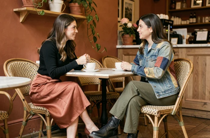 Deux femmes tendance dans leurs tenues de saison attablées dans un café parisien au décor terracotta